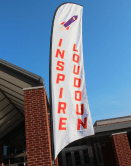 A picture of an Inspire Loudoun falcon flag flying in front of a school.